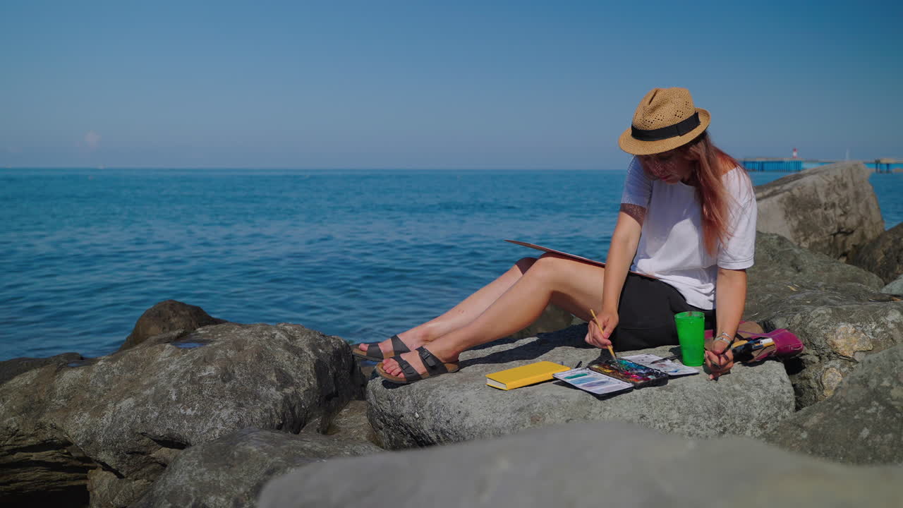 mujer pintando paisajes marinos en la playa