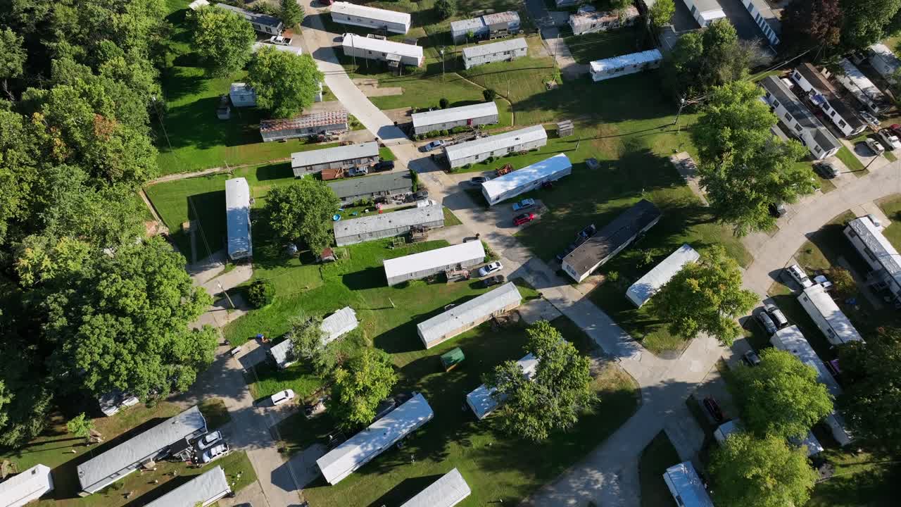 Sorvolo aereo di un parcheggio rimorchi sulla strada di una foresta americana in Virginia durante una giornata di sole. Quartiere con case mobili per vacanza o per viverci. Ripresa dall'alto