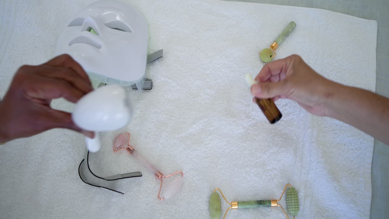 Hænder rækker ind, tager en grøn rulle og en pipetteflaske, mens de organiserer redskaber på et håndklæde.