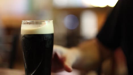 a person pours a dark beer into a glass.