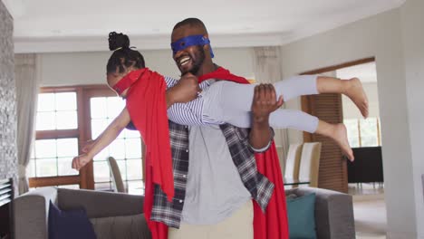 happy african american father and daughter having fun, wearing superhero costumes