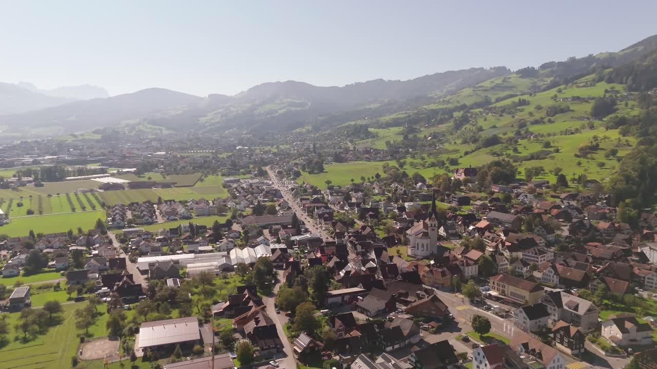 Foggy morning in traditional Swiss town during sunny day. Historic church and buildings in summer. Aerial wide shot. Marchbach, switzerland