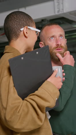 Vertical-Video-Of-Female-Film-Director-Talking-With-Male-Camera-Operator-Shooting-Movie-Or-Video-In-Studio-1