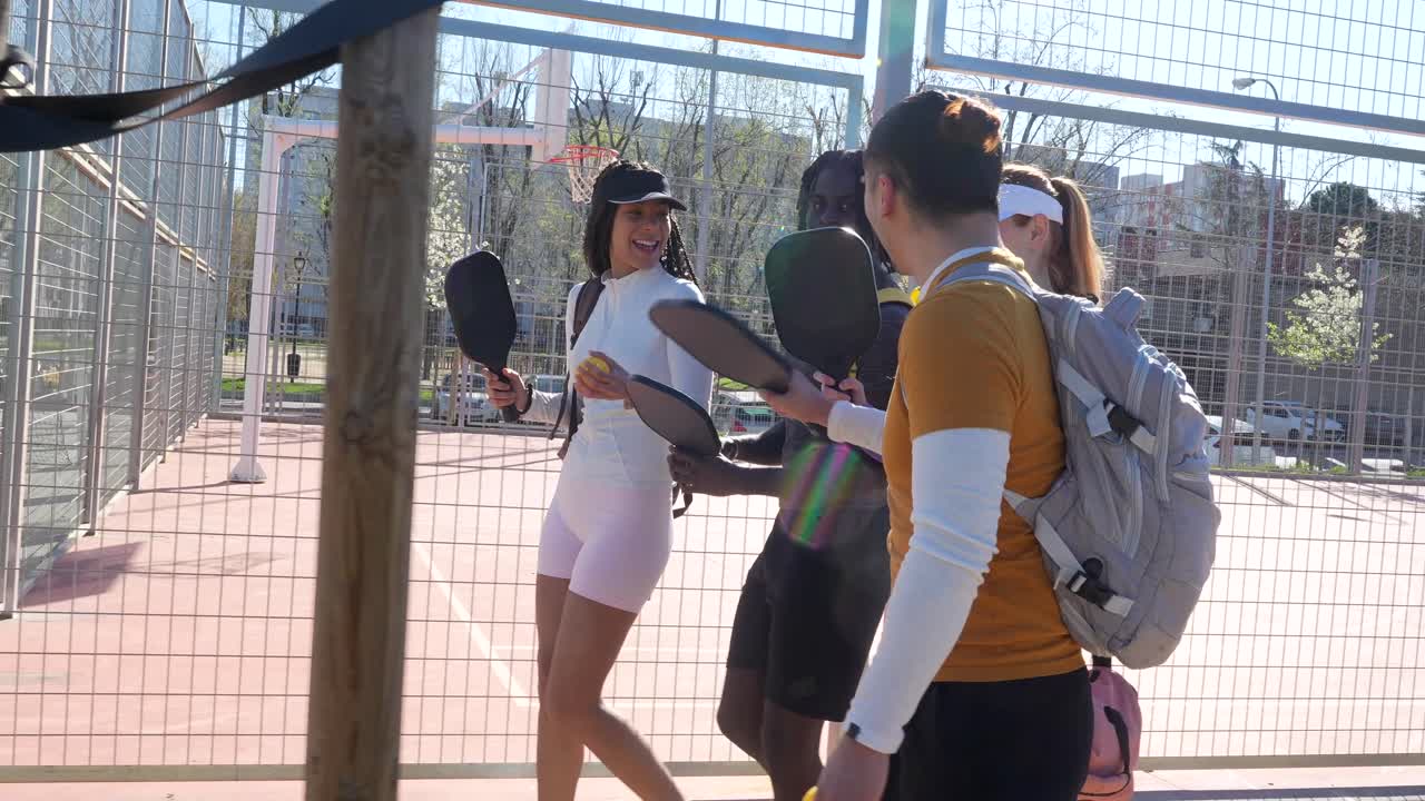 Giovani adulti felici che entrano nel campo da pickleball con le racchette