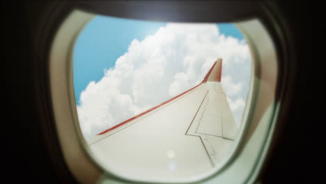 Toma-De-La-Ventana-Del-Avión-Con-Cielos-Azules-Y-Vista-De-Paisaje-Nuboso