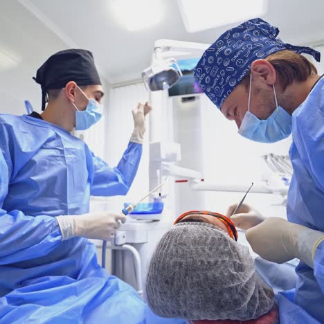 male dentist and his assistant in modern cabinet. orthodontist treating patient's teeth. assistant uses medical tools in dentistry.