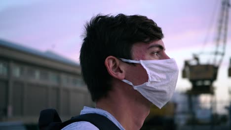 young man in face mask contemplating in city at dusk