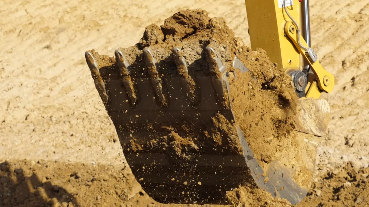 Yellow excavator digging the ground in slow motion, Close up