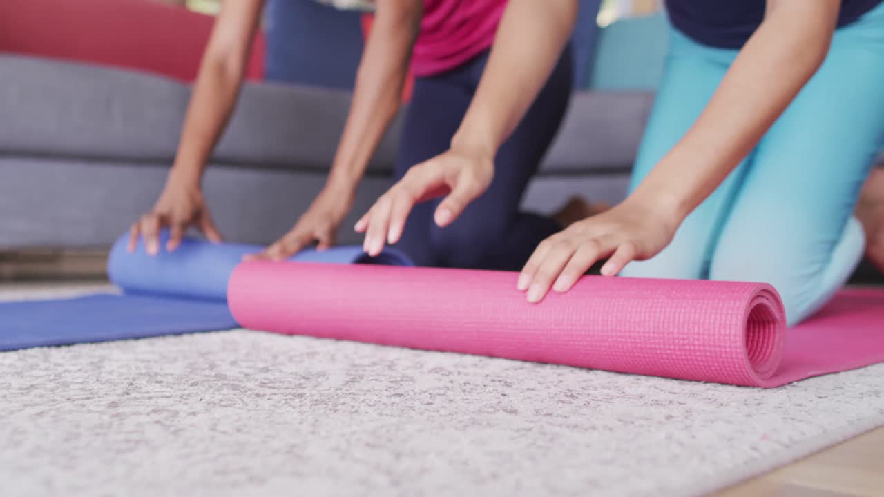 video de la sección media de diversas amigas rodando esteras de yoga en casa