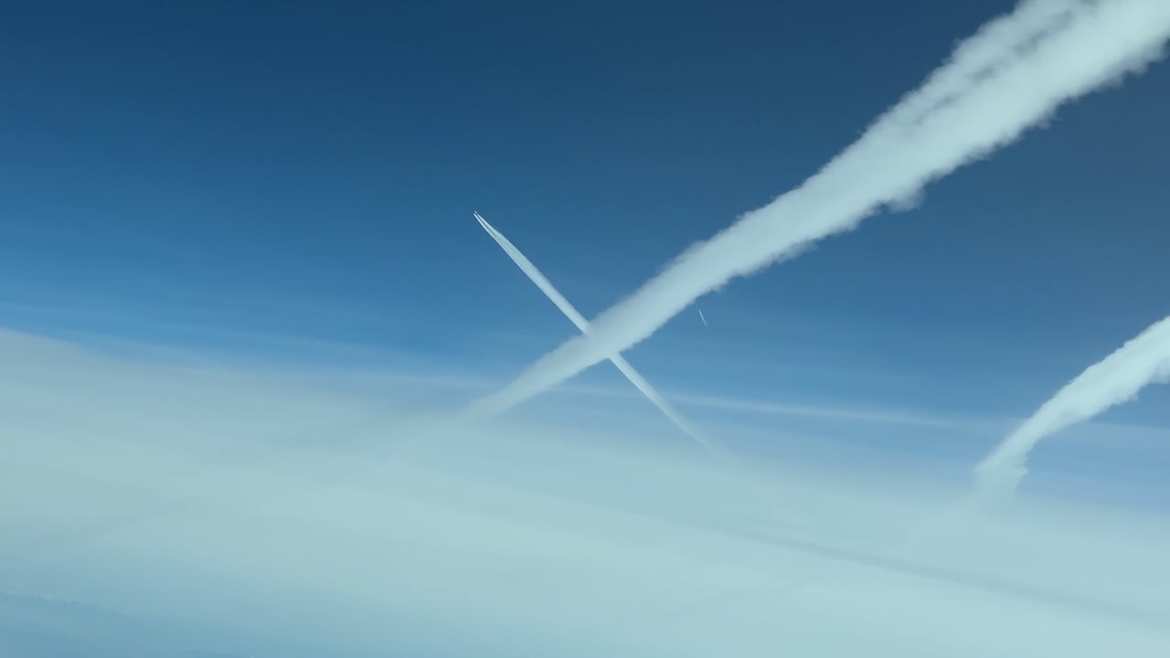 immersive cockpit view of multiple fgading contrails in a blue sky, captured from another jet flying 300m bellow in the stratosphere.