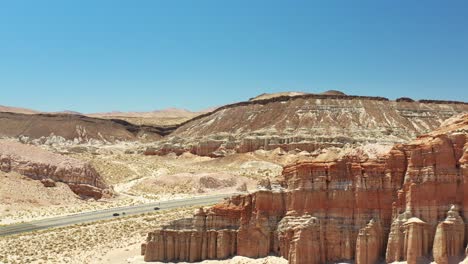 Highway-14-Midland-Trail-along-red-sandstone-cliffs-in-the-Mojave-Desert---aerial-view