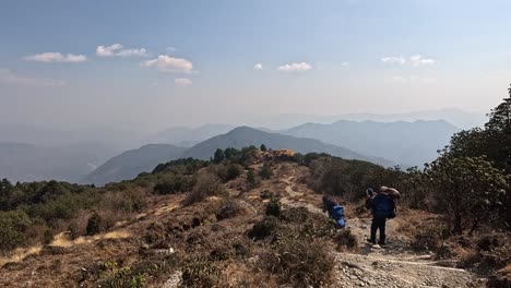 Sherpas with heavy backpack descending from a mountain trek on stair. Open Panoramic mountain landscape. Nepal Himalaya