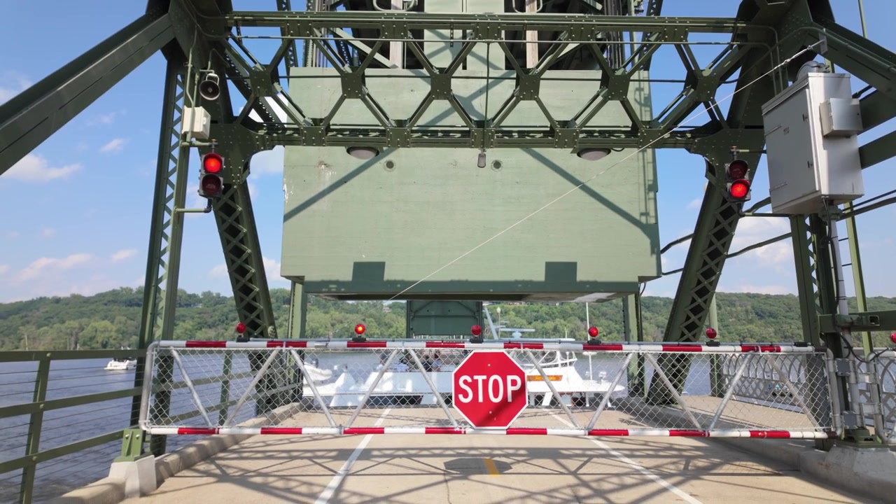 Gimbal close booming down shot of a riverboat passing through the raised lift bridge on the St. Croix River in Stillwater, Minnesota. 4K