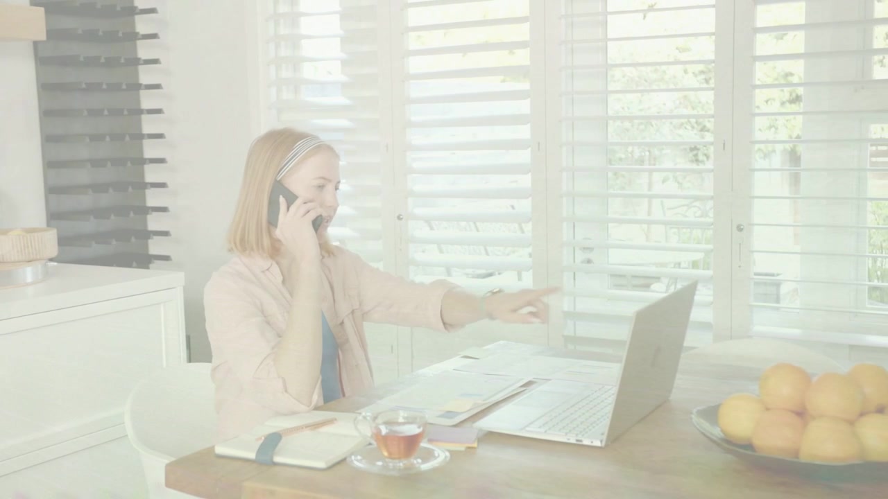 Ricevendo una chiamata, una donna gestisce lo smartphone, digita al laptop e legge documenti per lavoro