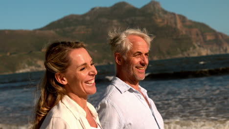 happy mature couple walking on the beach together