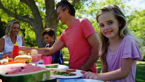 Mädchen-Sitzt-Am-Tisch-Und-Isst-Mit-Ihrer-Familie-Im-Park-4k