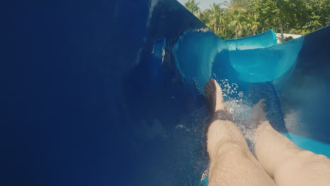 un hombre desciende de un tobogán de agua mirando solo los pies