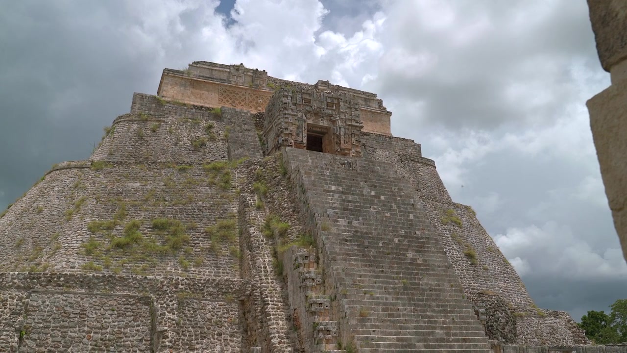 Inquadratura grandangolare statica dal basso della ripida scalinata in pietra che conduce al tempio superiore della Piramide dell'Indovino a Uxmal nello Yucatan, Messico.