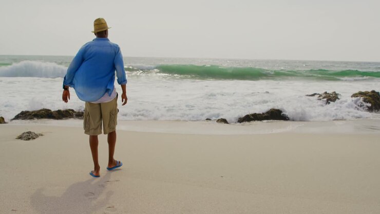 Vista posteriore di un uomo afroamericano che cammina sulla spiaggia 4k