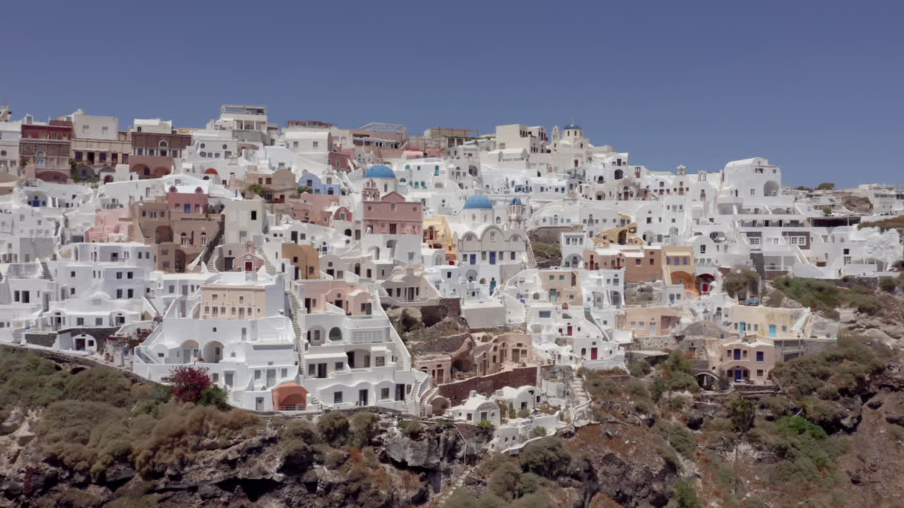 antena: dron panorámico lento tomado de oia en santorini, grecia en un día soleado