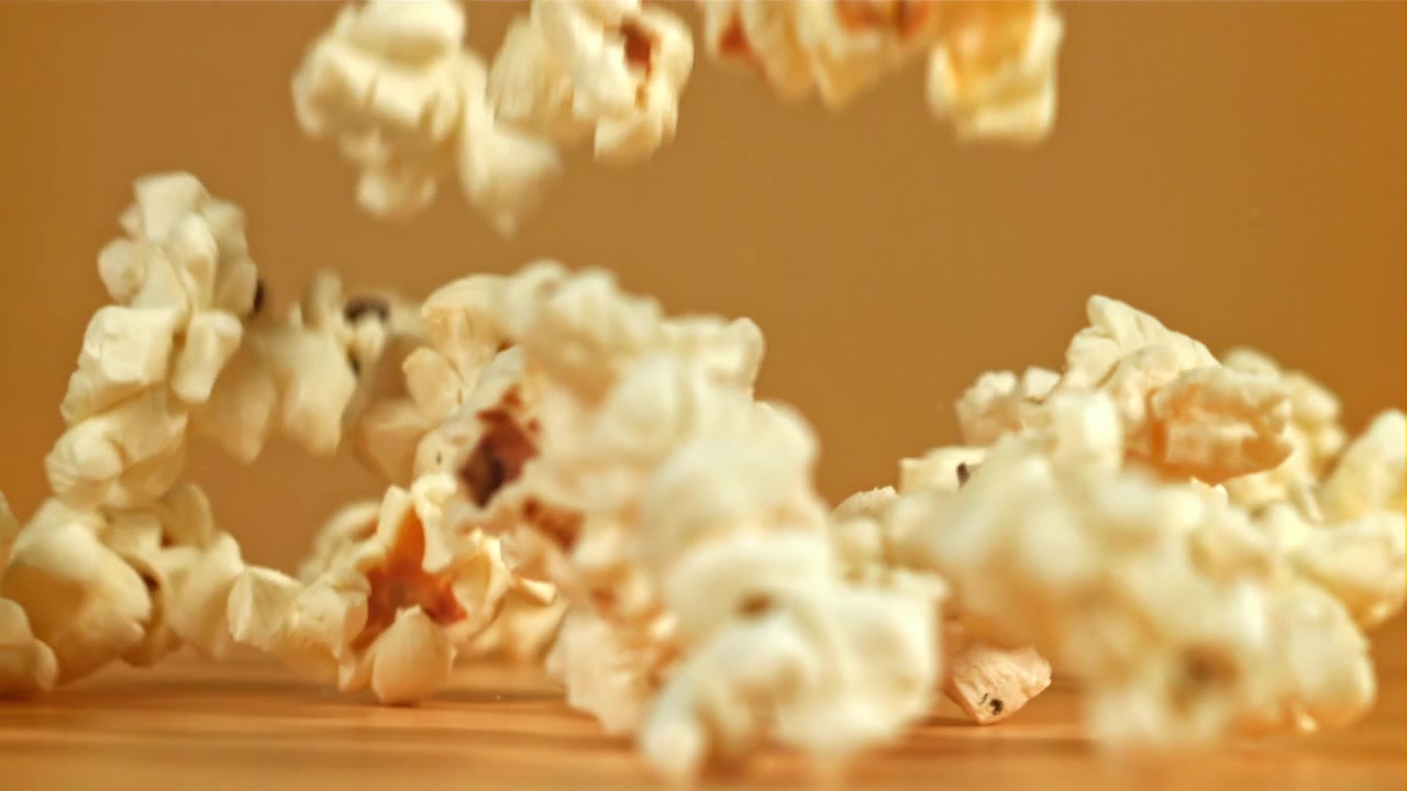 Popcorn che cadono al rallentatore su sfondo marrone