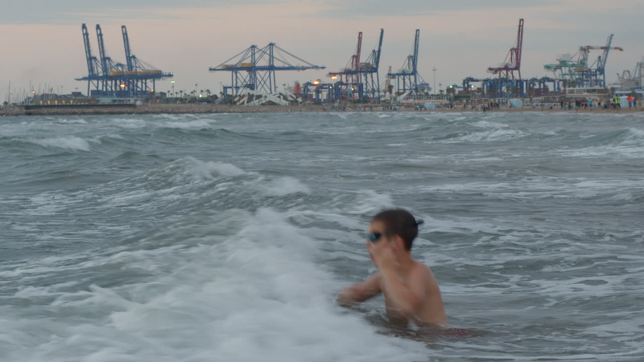 niño luchando con las olas del mar