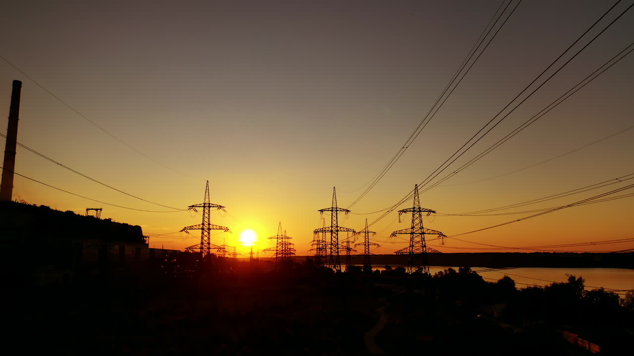 Dark electric towers against beautiful sunset. High-voltage electric lines in the evening on red and yellow sky.