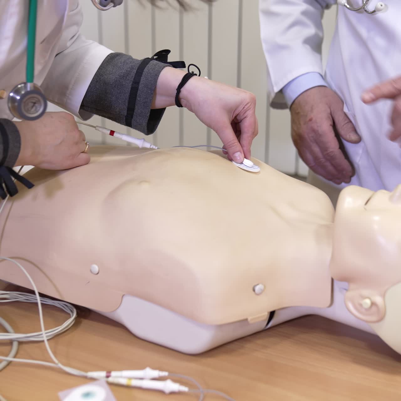 Hands on CPR practice dummy. Plastic dummy with connected life support sensors on hospital bed