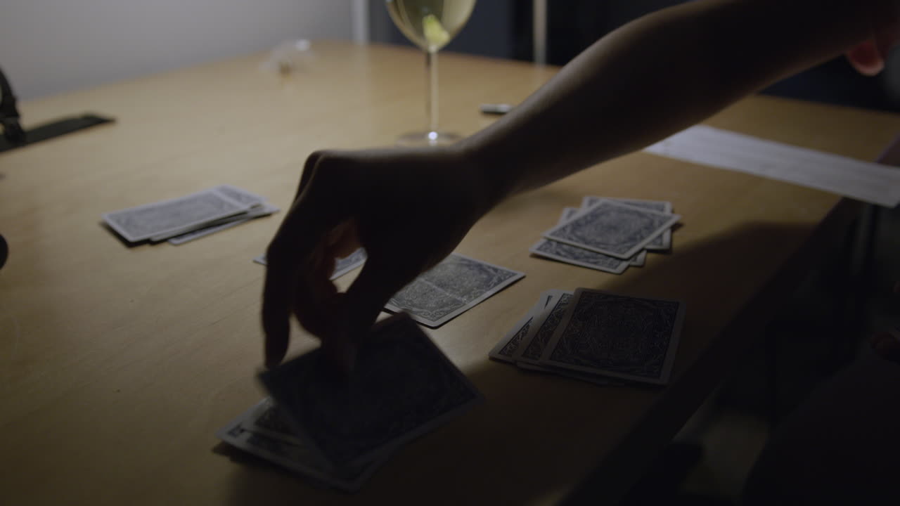 el hombre reparte naipes en una mesa con una iluminación tenue y malhumorada