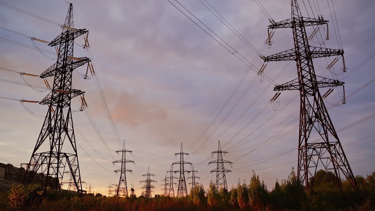 High-voltage electric towers at sunset. Transmission lines on field on the evening sky background. Electricity distribution. View from below.