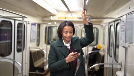 businesswoman in subway wagon using smartphone to send business email or text message to family