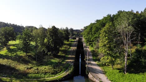 Old-lock-used-by-boats-to-go-up-river-in-rural-Sweden,-rising-aerial