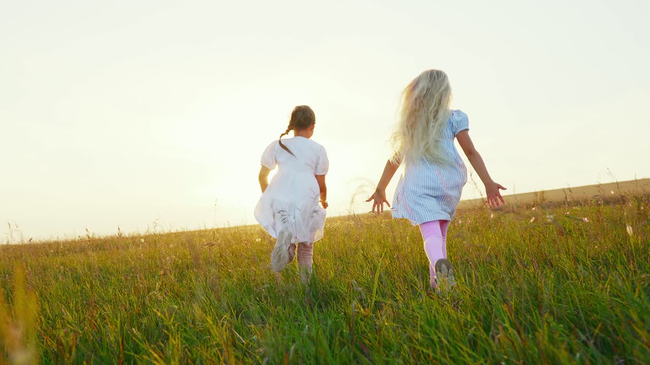 Due giovani ragazze che corrono attraverso un campo erboso al tramonto