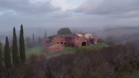 reveal shot of empty deserted farm house building in rural italy, aerial