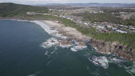 rocky burgess beach and coastal town of forster on vegetation-covered bluff in new south wales, australia