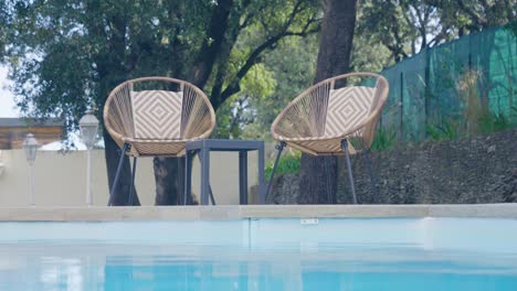 rotating shot of two white wicker poolside chairs