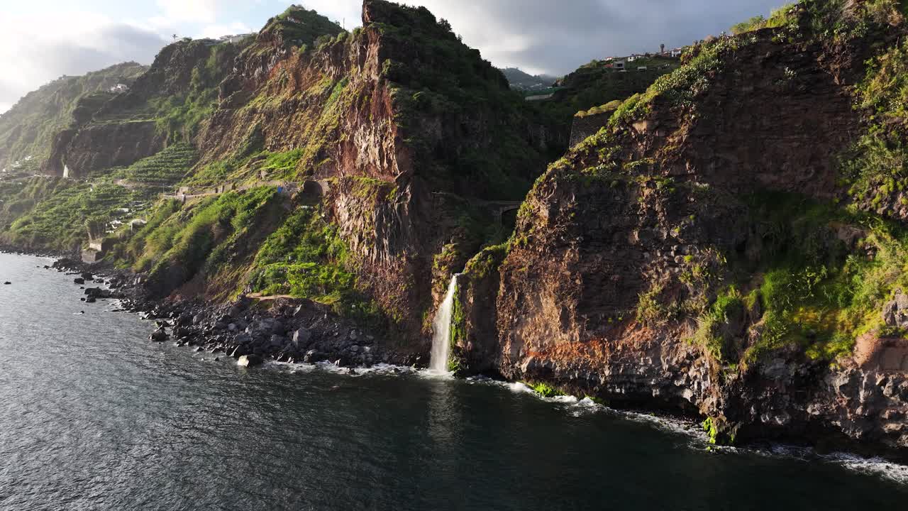 Scenic Cascata do Mito plunging over cliff face into ocean on Madeira. Aerial