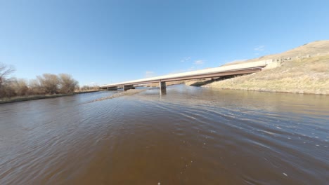 Drone-De-Carreras-Fpv-Volando-Bajo-Y-Rápido-Sobre-El-Agua-Del-Río-En-Montana,-Estados-Unidos