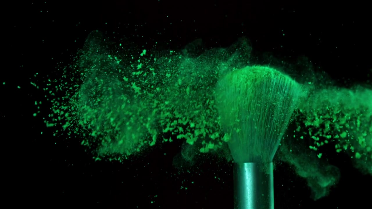 Levende grønt pulver eksploderer fra makeupbørste i slowmotion