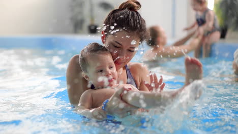 mamá joven en la piscina jugando con su hija en cámara lenta. familia deportiva dedicada a un estilo de vida activo