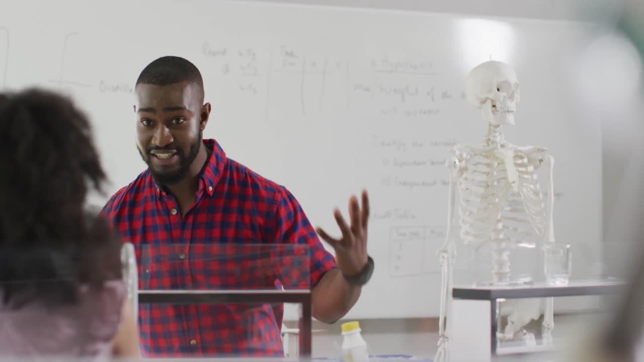 Video of happy african american teacher with class of diverse pupils during anatomy lesson