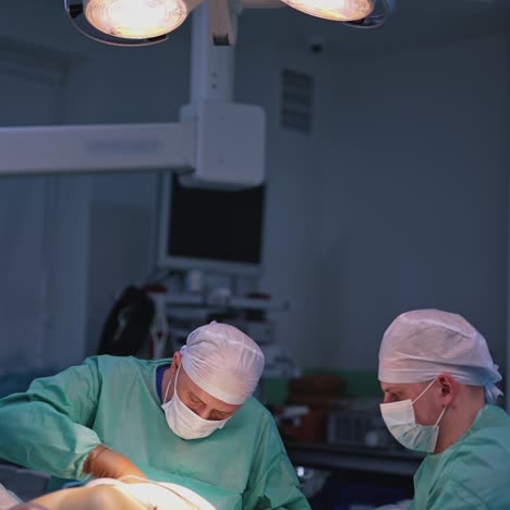 male doctor and assistant performing a surgery. medical specialists in masks doing plastic surgery to a patient in the hospital. health care concept