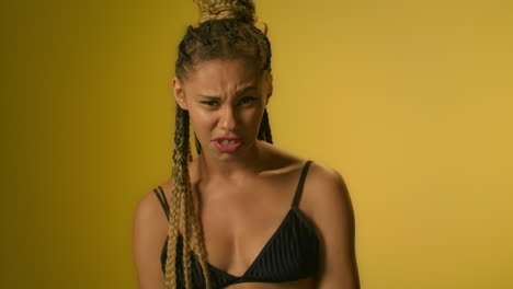 Angry-woman-screaming-and-swearing-on-yellow-wall-background-in-studio