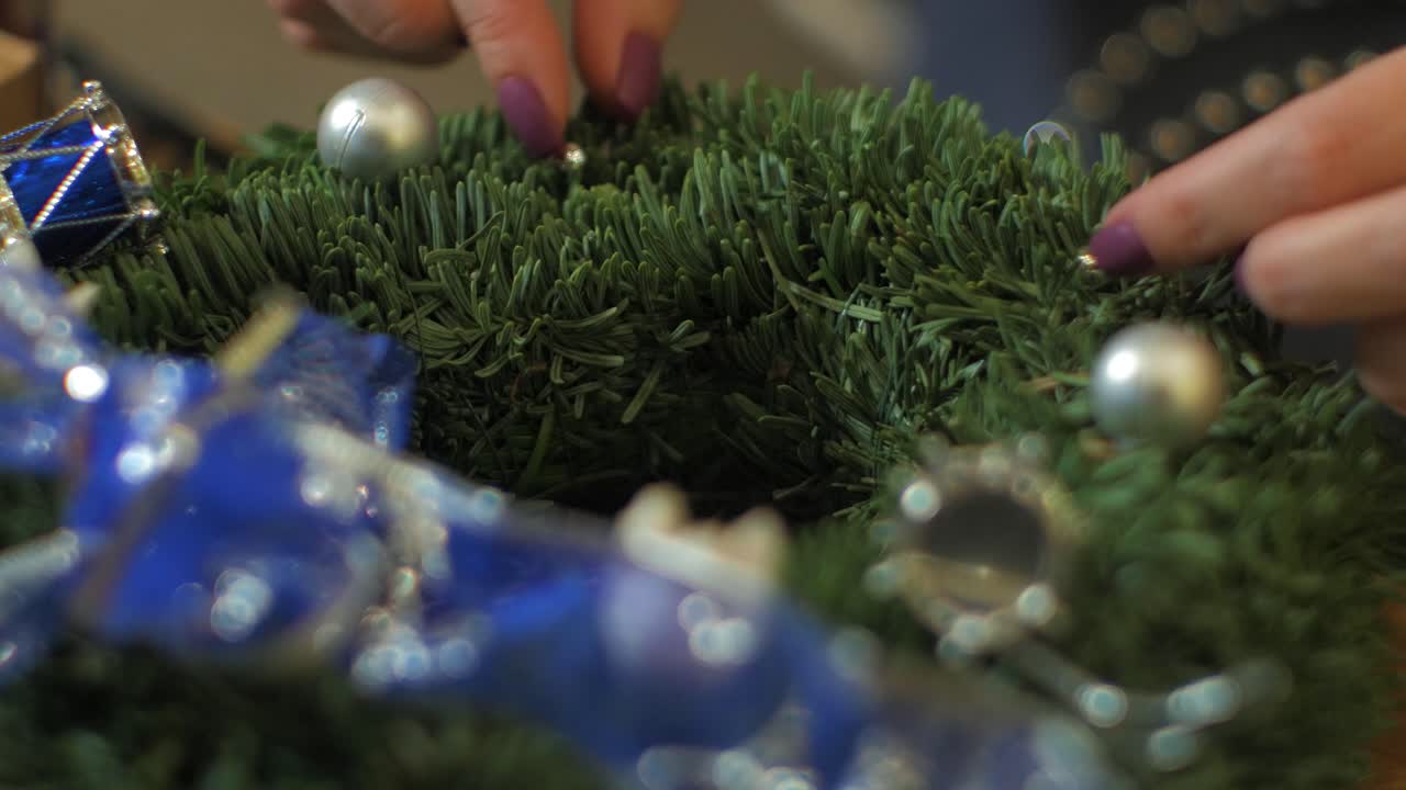 mujer haciendo una corona de abeto para la víspera de navidad y decorándola con perlas de plata, decoración artesanal diy, tradiciones de invierno, vacaciones de temporada, manos de cerca