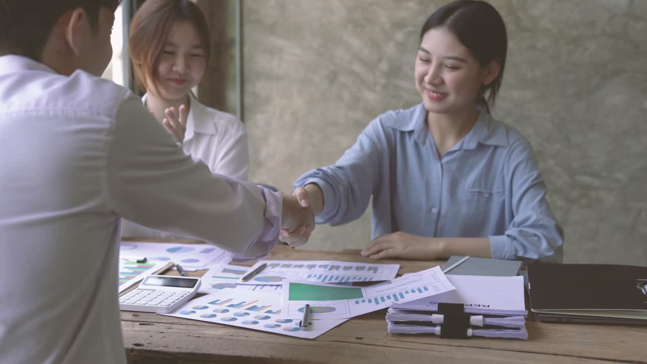 Young Asian business people shaking hands in the office. Finishing successful meeting. Three persons.
