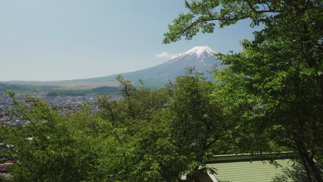 vista cubierta de nieve del monte fuji vista a través de árboles verdes en un día despejado con cielos azules en fujiyoshida