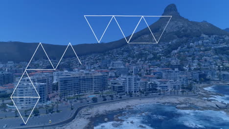 white triangles floating above coastal cityscape, showing mid-rise buildings lined by ocean waves