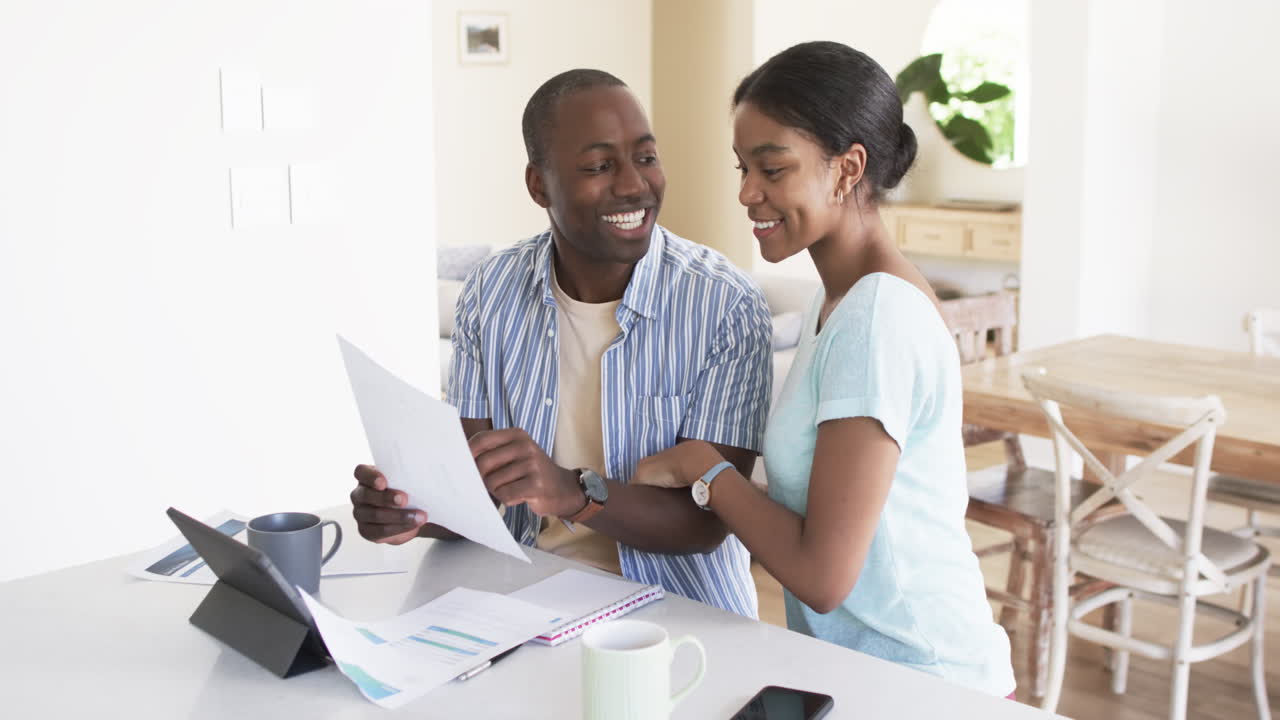 A young African American couple reviews bills and invoices using a tablet