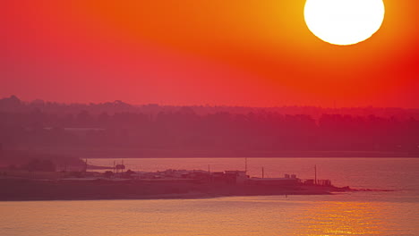 enormous red sunrise above landscape silhouette, time lapse view