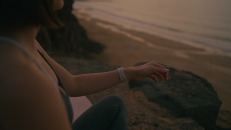woman checking smartwatch on the beach at sunset